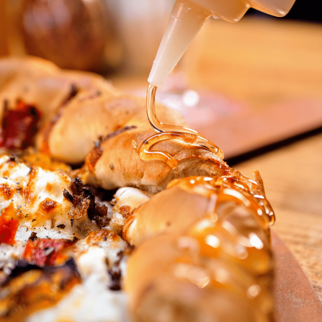 honey being dripped on a pizza crust