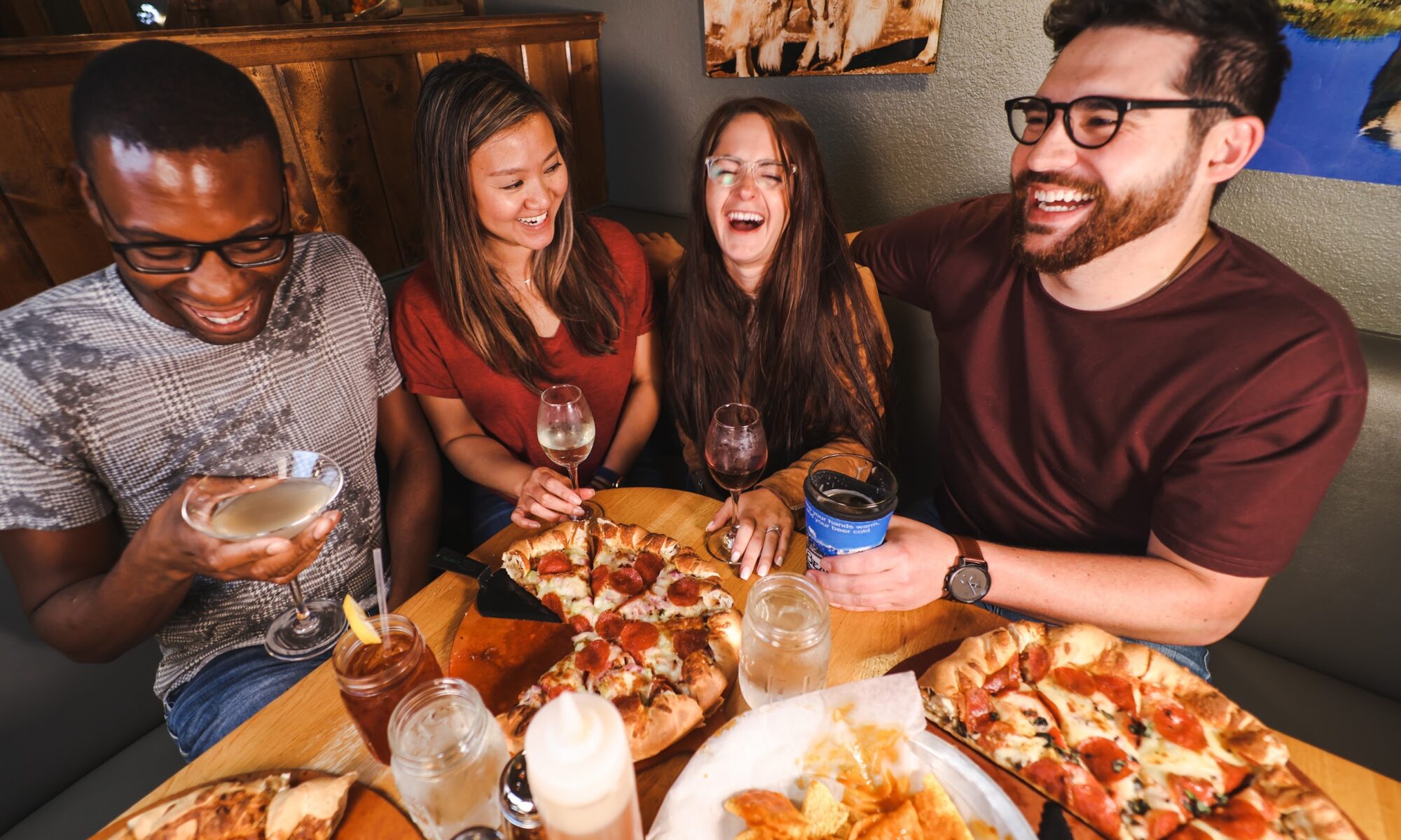 people sitting around a table filled with pizza and beverages