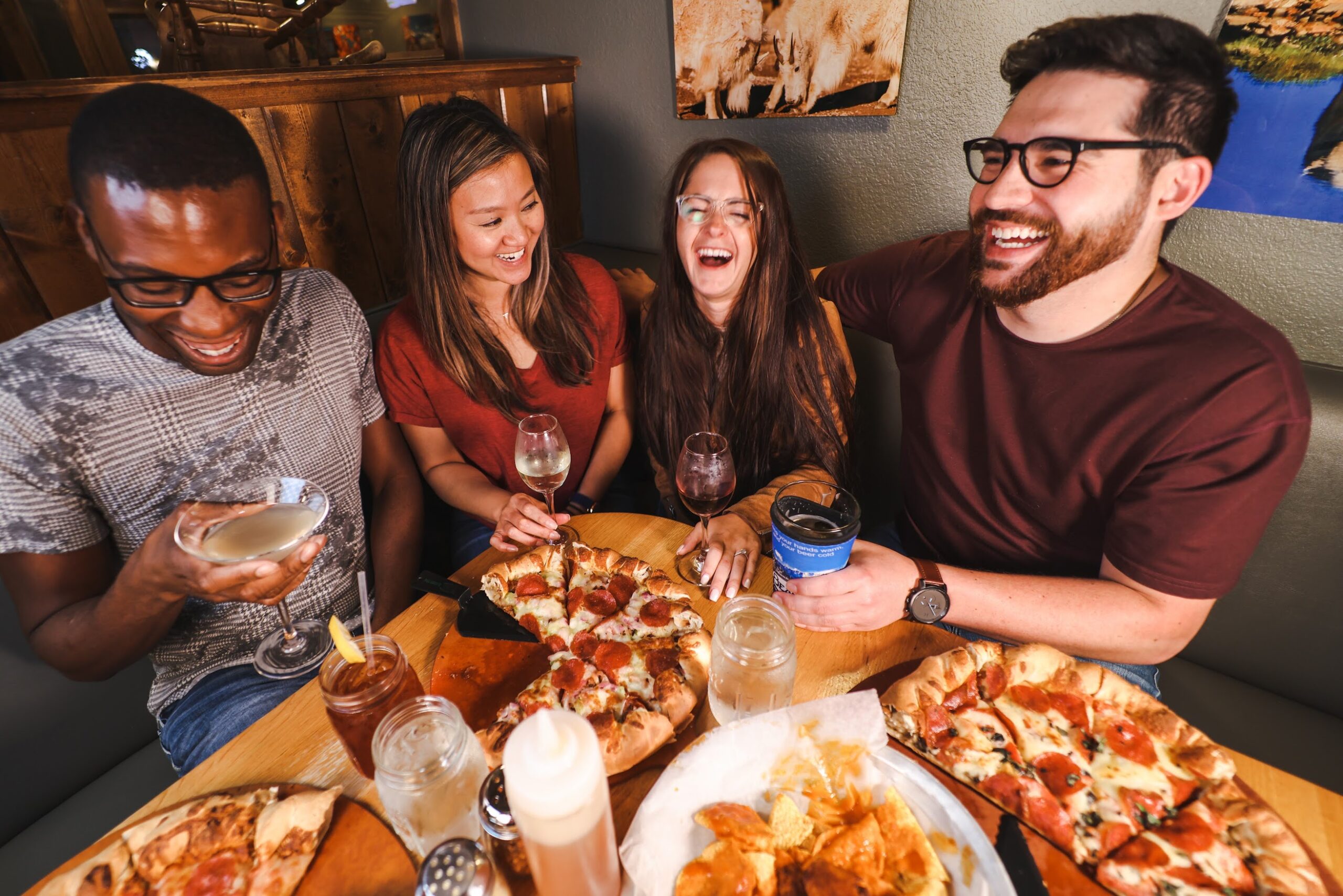 people sitting around a table filled with pizza and beverages